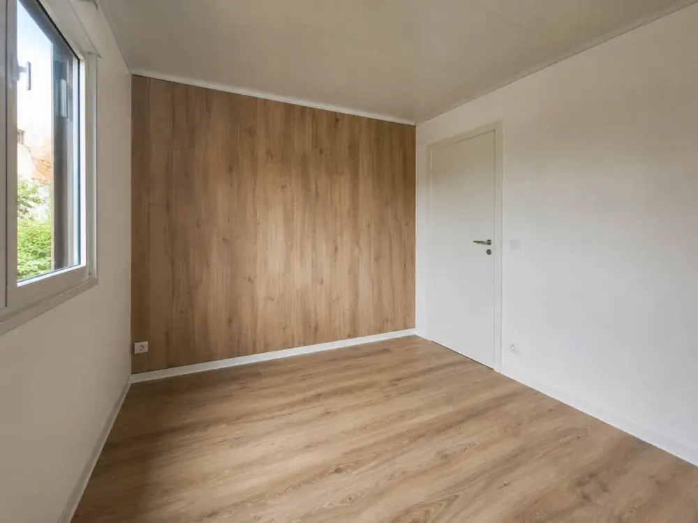 Interno di un container abitativo con pavimento in laminato e parete in legno