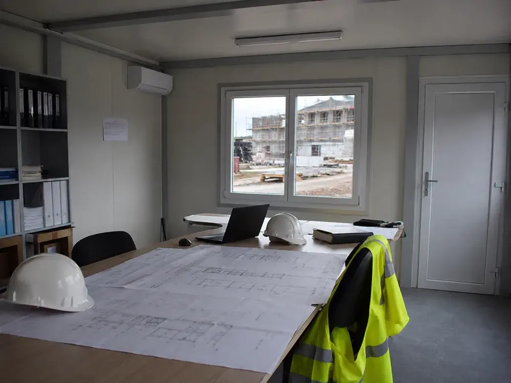 Interno di un ufficio di cantiere con i disegni tecnici sul tavolo
