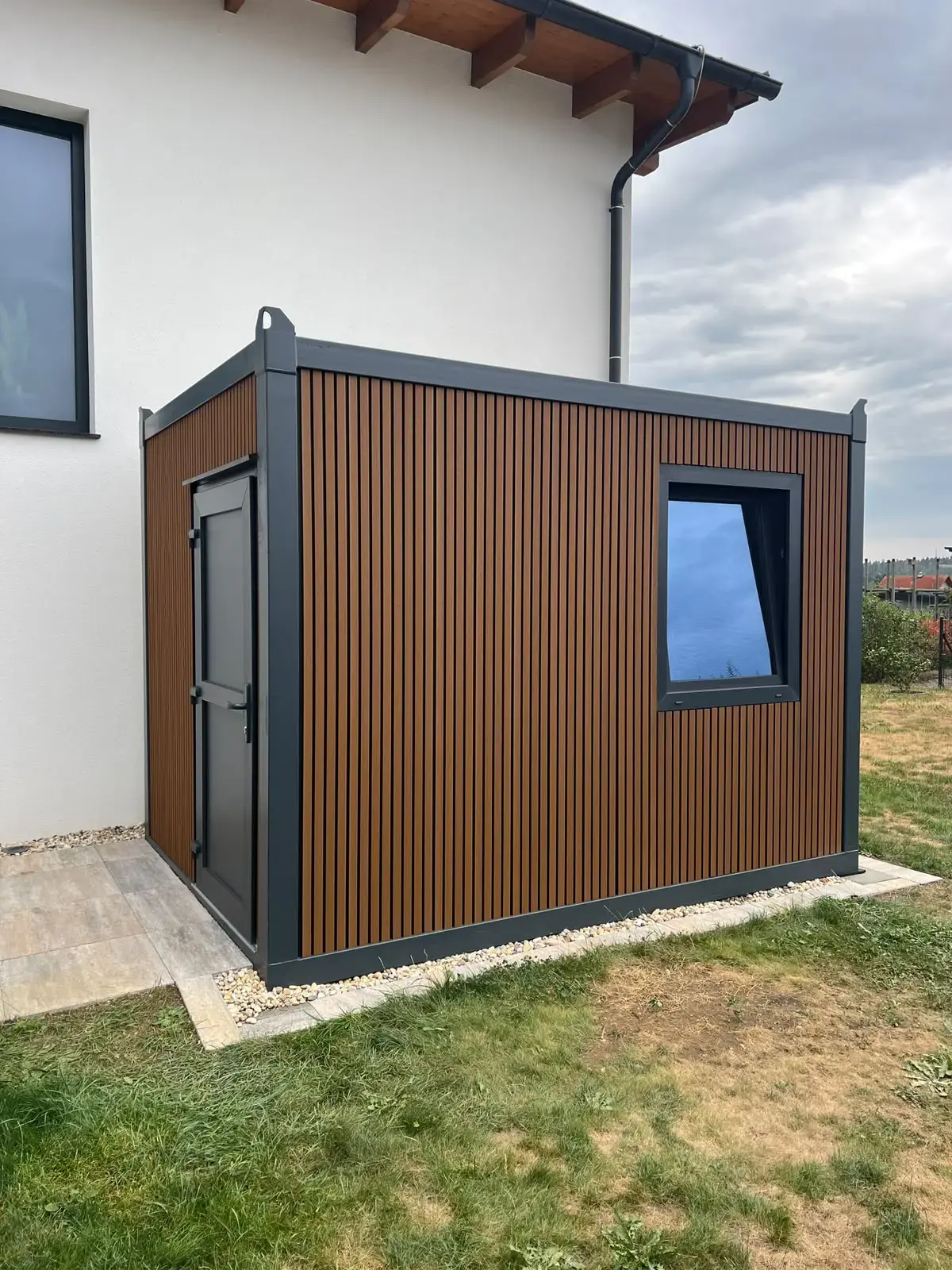 Container con facciata in WPC accanto a una casa